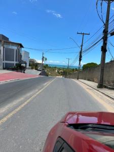 una calle vacía con un coche rojo estacionado en la carretera en Apartamento da Jana a 1,5km praia en Porto Seguro