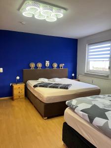 1 dormitorio con 2 camas y pared azul en Ferienwohnungen Wotan, en Thale