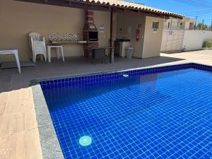 une piscine bleue en face d'une maison dans l'établissement Apartamento da Jana a 1,5km praia, à Porto Seguro