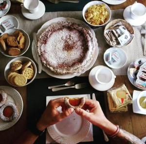 una persona sosteniendo un donut frente a una mesa de comida en Lady Food Location, en Cava deʼ Tirreni