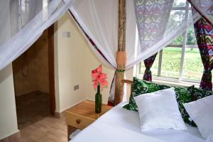 um quarto com uma cama e um vaso com flores sobre uma mesa em Kilimanjaro Accommodation em Msaranga