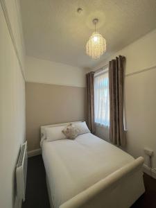 a bedroom with a white bed and a chandelier at New Derina Hotel in Blackpool