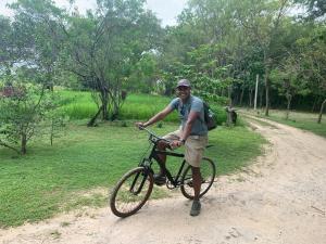 um homem segurando uma bicicleta em uma estrada de terra em Sahana Retreat em Buttala