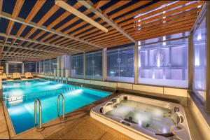 a large swimming pool with a tub in a building at Crown Rose Al Sahafa Hotel in Riyadh