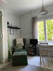 een woonkamer met een bank, een stoel en een raam bij Viehättävä yksiö merellisessä Kotkassa. in Kotka