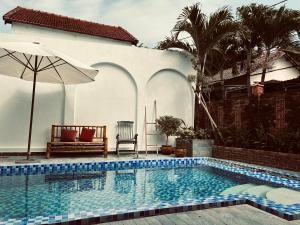 a swimming pool with an umbrella next to a house at Soleil de An Bang Villa in An Bàn (2)