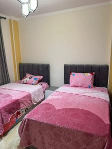 two beds in a room with pink sheets at عباس العقاد مدينه نصر in Cairo