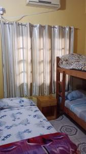 1 dormitorio con 2 camas y una ventana con cortinas en Alvar Nuñez en Puerto Iguazú