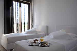 two beds in a hotel room with a tray of food at Pietre Nere Resort & Spa in Modica