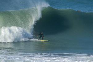 un homme faisant une vague sur une planche de surf dans l'océan dans l'établissement Joaquina Guest House, à Florianópolis