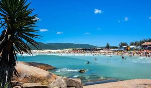 a beach with a bunch of people in the water at Joaquina Guest House in Florianópolis
