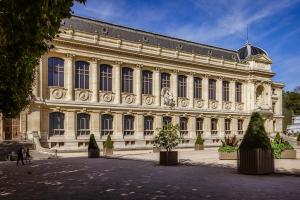 un gran edificio con árboles delante de él en Appartement service - Vue sur le Musée - Paris 5, en París