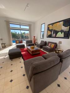a large living room with couches and a red rug at Dar Essa a Essaouira, personnel inclus, piscine chauffée in Essaouira