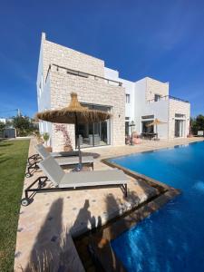 une villa avec une piscine et un parasol dans l'établissement Dar Essa a Essaouira, personnel inclus, piscine chauffée, à Essaouira
