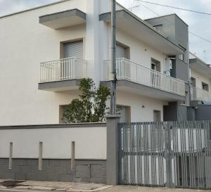 un edificio bianco con balconi e recinzione di Casa Vacanza Casale a Brindisi