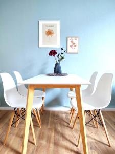 a dining room table with white chairs and a vase with flowers at Steinstraße alt gelöscht in Bad Salzuflen