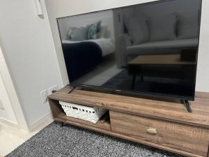 TV de pantalla plana en un centro de entretenimiento de madera en Apartment Namba Style 201 en Osaka