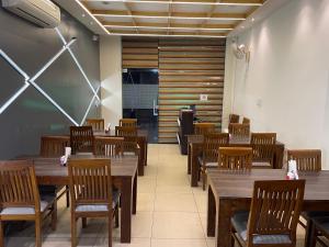 una sala da pranzo con tavoli e sedie in legno di Hotel Paradise Dream a Ludhiana