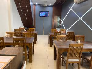een restaurant met houten tafels en stoelen en een tv aan de muur bij Hotel Paradise Dream in Ludhiana