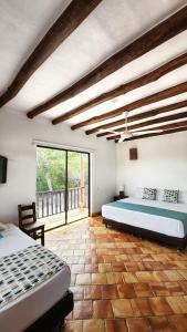 a bedroom with two beds and a large window at Hotel AMANEE in Barichara