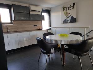 eine Küche mit einem Tisch mit Stühlen und einem Gemälde eines Mannes in der Unterkunft L'Orlu Chambres D'Hotes proximité plage in Canet-en-Roussillon