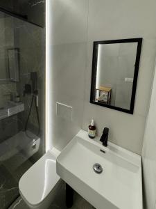 a white bathroom with a sink and a mirror at Apartmánové ubytovanie POD DUBOM in Poľný Kesov