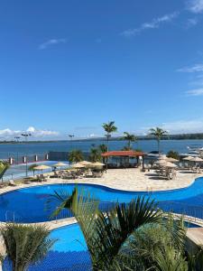 a large swimming pool with umbrellas and a beach at Flat beira lago no centro de BSB in Brasilia