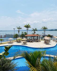 a large pool with tables and umbrellas and the ocean at Flat beira lago no centro de BSB in Brasilia