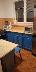 una cucina con armadi blu e bancone con forno a microonde di Bugenwilla Apartament a Sopot