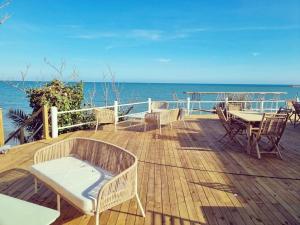 una terraza de madera con mesas y sillas y el océano en Bahía de Montecarlo en Alcanar