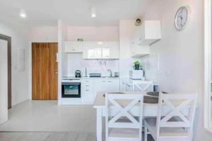 a kitchen with white cabinets and a table and chairs at Central Apartments & Wal25C in Gdańsk