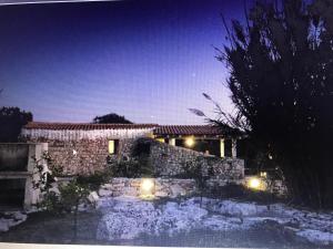 - une maison en pierre avec des lumières dans la cour dans l'établissement Feudo Frammasi - Curte Glamping Experience, à Salve