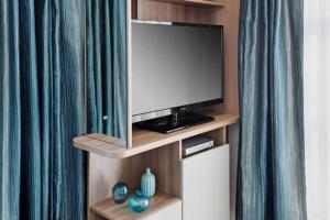 a flat screen tv sitting on a wooden entertainment center at The CaraPod & HotTub - KINTYRE in Tarbert