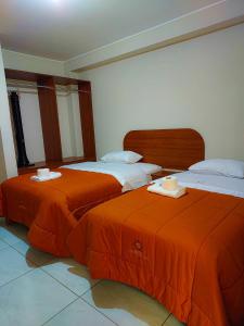two beds in a room with orange sheets at HOTEL CENTRAL INN in San Juan