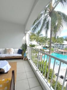 balcón con sofá y vistas a la playa en Peppers Beach Club Penthouse en Palm Cove