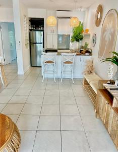 Il comprend une cuisine dotée de carrelage blanc, d'une table et de chaises. dans l'établissement Peppers Beach Club Penthouse, à Palm Cove