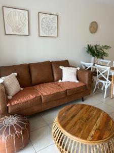 a living room with a brown couch and a table at Peppers Beach Club Penthouse in Palm Cove