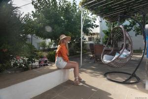 a woman is sitting on a wall next to a swing at Villa Alexandra in Exámbela +66 photos