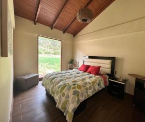 sypialnia z łóżkiem z czerwonymi poduszkami i oknem w obiekcie Sacred Valley House w mieście Calca