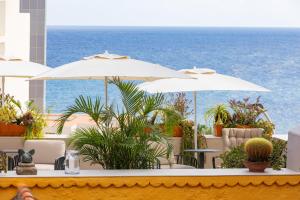 a patio with tables and umbrellas and the ocean at Hotel San Telmo in Santa Cruz de la Palma