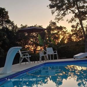 een zwembad met 2 stoelen en een parasol bij casa rosa in Cotia