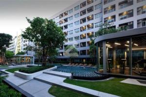 a large building with a swimming pool in front of it at Elio Sukhumvit 64: Chic Space in Bangkok