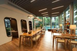 a restaurant with wooden tables and chairs and windows at Elio Sukhumvit 64: Chic Space in Bangkok