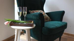 una silla verde y una mesa con dos copas de champán en Apartmán Spálený mlýn, en Líšnice