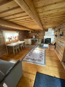 a large living room with a wooden ceiling and a table at Pine Tree Cabin in Glommersträsk