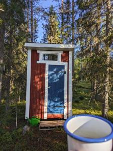 a outhouse with a door in the woods at Pine Tree Cabin in Glommersträsk