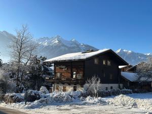 a house in the snow with mountains in the background at Woodyard in Piesendorf