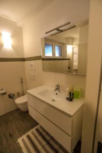 a bathroom with a sink and a toilet and a mirror at Tizi House in Varenna