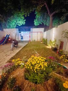 un jardín con flores y un parque infantil por la noche en Airport Hotel Bed & Rest en Karachi