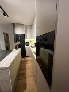 a kitchen with white cabinets and black appliances at Apartman 15 in Jahorina